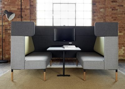 Rectangular grey and light green fabric meeting or dining booth with integrated table and TV screen
