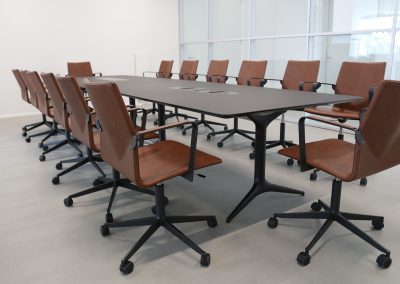 Designer brown leather and black base boardroom chairs with arms around a large black finish boardroom table