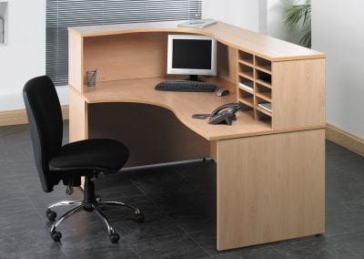 Back view of a wood veneer reception desk with desktop storage unit and black and chrome operators chair