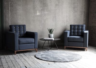 Dark blue occasional armchairs with yellow stud buttons, dark wood feet and black wireframe coffee table