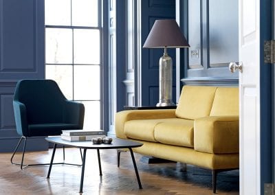 Yellow two seater sofa with black legs, blue occasional chair with black wireframe legs and complimenting black coffee table