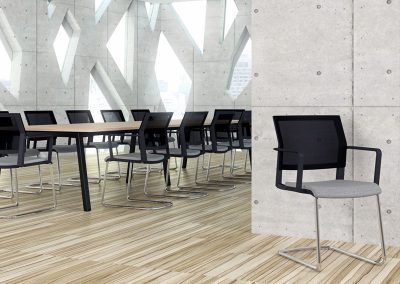 Boardroom chairs with grey fabric seats, black mesh backs and chrome frames around a large wood effect boardroom table with black legs