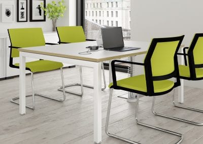 Four meeting chairs with lime green seat and back pads, black upper and chrome lower frame, around a rectangular white meeting table