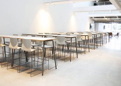 Photograph of rows of stools with white seats around long tables
