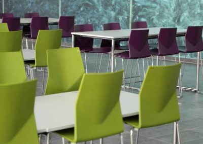 Breakout or dining tables with white tops and chrome legs with moulded lime green and purple chairs with chrome wireframe legs