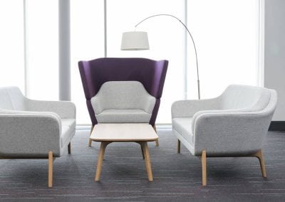 Light grey fabric low back sofas with natural wood legs, matching occasional chair with high back in purple fabric and complimenting natural wood coffee table