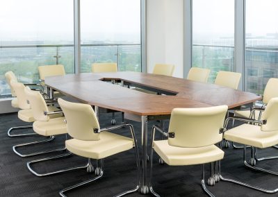 Cream leather and chrome boardroom chairs with arms around a walnut and chrome boardroom table