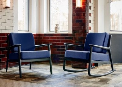 Two black finish wood occasional chairs, one in a rocking chair style, both with blue fabric seat cushions