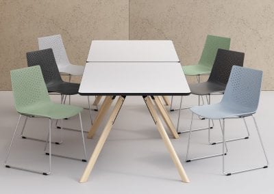 Modern looking moulded plastic meeting chairs with chrome wire frames around white top tables with light wood legs