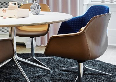 Designer retro look meeting or dining chairs in brown leather and blue patterned fabric with chrome bases and matching circular meeting table