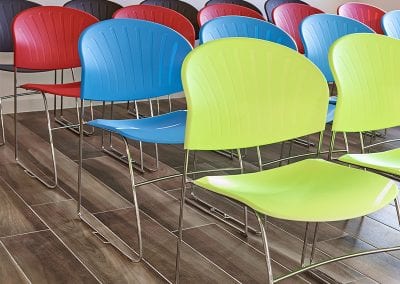4 rows of plastic meeting chairs with chrome wire frames and shown in lime green, bright blue, red and black seat options