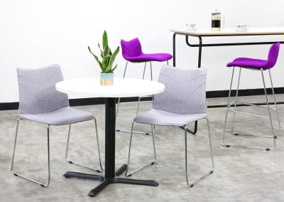 Circular breakout or dining table with chrome wireframe chairs with grey fabric covers and high table with matching wireframe high stools