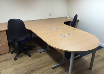 Two workstations positioned back to back to create a bespoke desk solution with additional straight and d-shape end desk, 3 drawer pedestal units and adjustable operator chairs