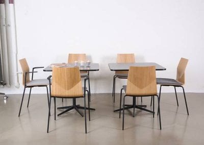 Black square breakout or dining tables with round corners, black legs and complimentary chairs with moulded wood veneer chairs