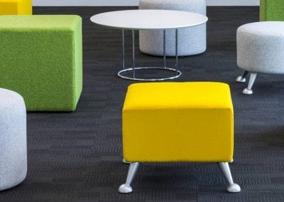 Yellow, green and grey stools, some with metal feet and a circular white coffee table