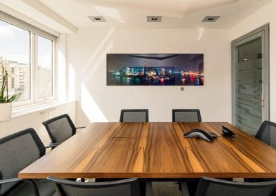 Solid wood square boardroom table with cable management, surrounded by black mesh backed boardroom chairs