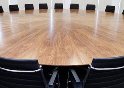 Large circular wood veneer boardroom table with black leather and chrome boardroom chairs