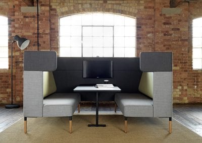 Grey and light green fabric covered double bench seat dining pod with integrated table and monitor screen