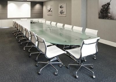 Large frosted glass boardroom table with chrome legs, surrounded by white leather and chrome boardroom swivel chairs.