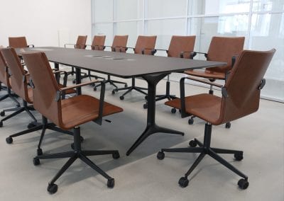 All black designer boardroom table with cable management and brown leather and black swivel boardroom chairs