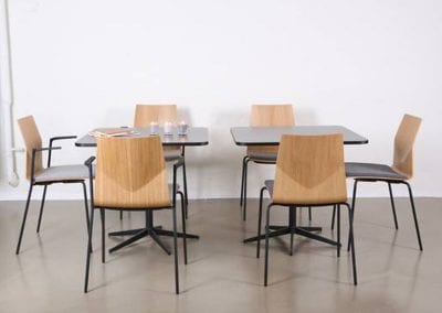 Square, all black dining or meeting tables with wood and black frame chairs for staff rooms