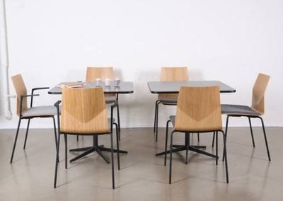 Square, all black dining or meeting tables with wood and black frame chairs for staff rooms
