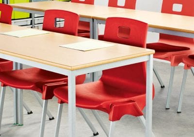 Wood top educational tables with grey metal legs and red stackable chairs