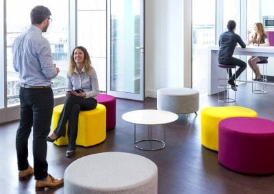 White topped circular coffee table with chrome legs surrounded by multi colour circular seats