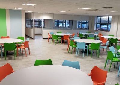 Circular white top dining tables with sturdy centre leg and base with multi colour plastic stacking chairs