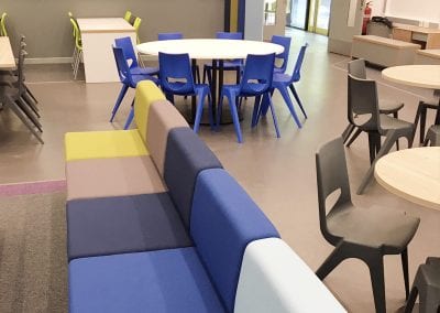 A selection of circular and bench style tables with stacking chairs in various colours and modular sofa seating