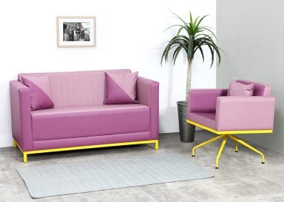 Staff room sofa and chair in pink upholstery with yellow frame feet