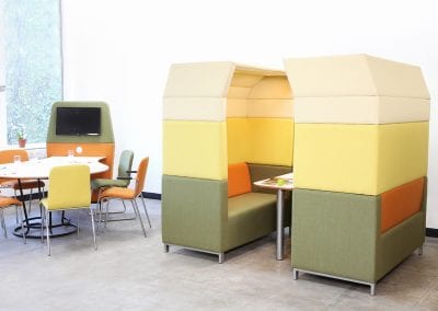 Staff room breakout meeting pod with two facing sofas and overhead canopies around a table