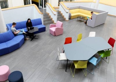 A large breakout area with a variety of seating solutions including modular sofas, occasional chairs, stools and table with multi colour stacking chairs
