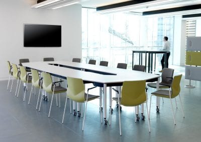 White meeting tables with castors formed in a long rectangular meeting table configuration with yellow and grey meeting chairs