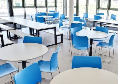 Circular and bench tables with blue molded chairs and bench seats