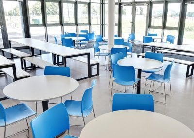 Circular and bench tables with blue molded chairs and bench seats
