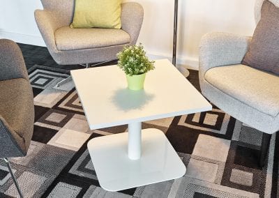 All white square coffee table with retro meeting chairs and rug