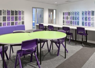 Green top circular interlocking tables with purple moulded plastic stacking chairs and matching swivel chairs, with built-in personal effects lockers
