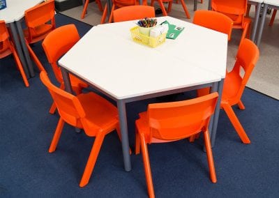 Hexagonal educational tables with metal legs and molded stacking chairs