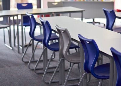 Grey top tables with metal frame legs and blue and grey plastic stacking chairs with metal frame legs