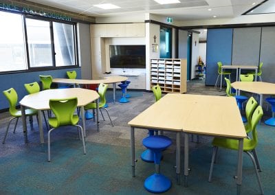 Wood effect height adjustable tables in a variety of shapes with lime green moulded plastic chairs and blue plastic moulded stools