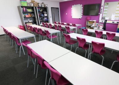 White top tables with metal frame legs and stacking plastic chairs with pink moulded seats and metal legs