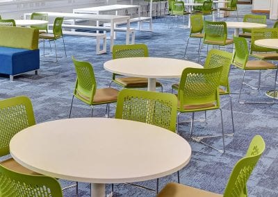 Staff room white circular tables with lime green mesh back chairs and white bench tables and bench seating