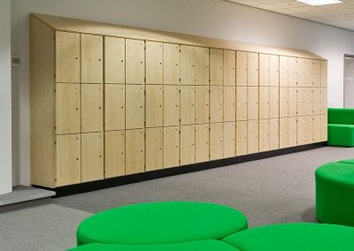 Wood veneer wall mounted personal lockers with slope top in a staff area with green casual seating