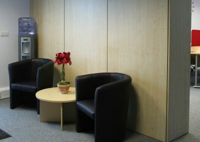 Wood veneer floor to ceiling wall storage units with complimenting tub chairs and coffee table