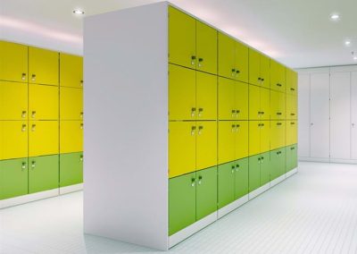 Locking wall storage lockers with yellow and green doors in a sports changing room