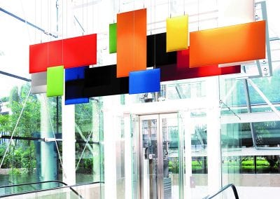 Suspended acoustic panels in various colour and size options hanging in a large open glazed area above esculators