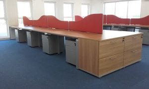 Wood veneer workstations with wheeled grey pedestals, orange fabric divider screens and matching veneer desk height drawer units