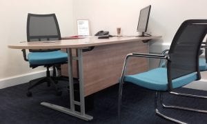 Veener task desk with grey metal legs and cable management ports with mesh back operator chair and matching meeting chairs