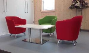 Designer tub chairs in red and green fabrics with chrome feet around a rectangular occasional table with chrome legs